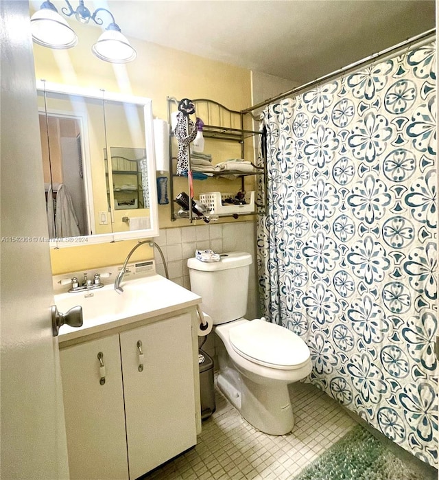 bathroom featuring tile patterned floors, vanity, toilet, and tile walls