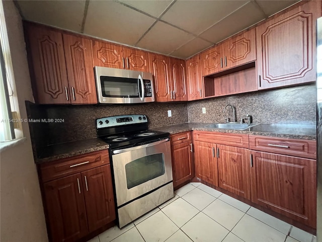 kitchen with light tile floors, backsplash, sink, and stainless steel appliances