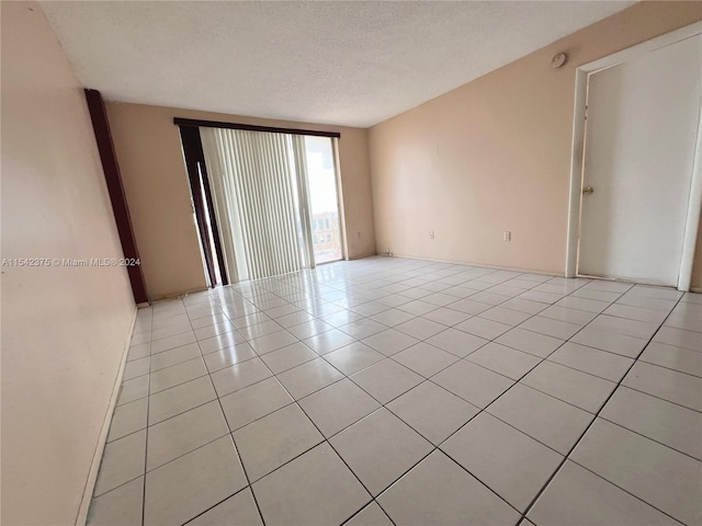 tiled empty room with a textured ceiling