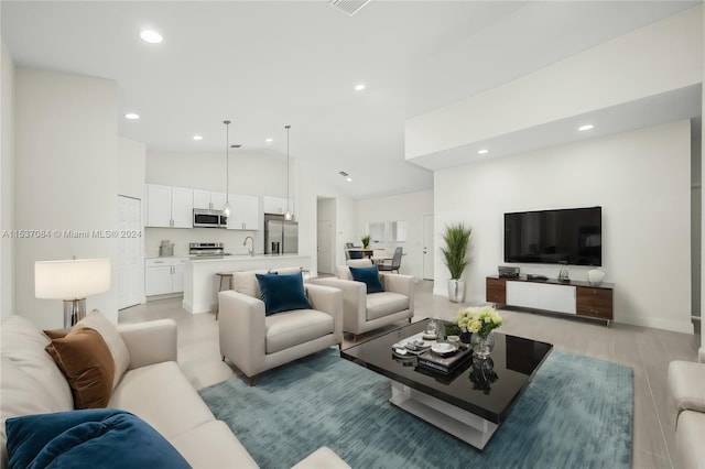 living room with high vaulted ceiling, sink, and light hardwood / wood-style floors