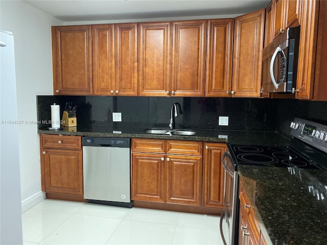 kitchen featuring light tile patterned floors, dark stone counters, backsplash, stainless steel appliances, and sink