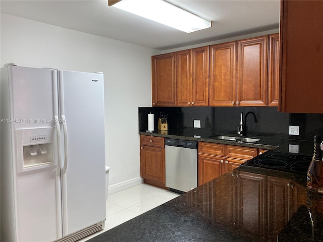 kitchen featuring light tile patterned flooring, white fridge with ice dispenser, dark stone counters, dishwasher, and backsplash