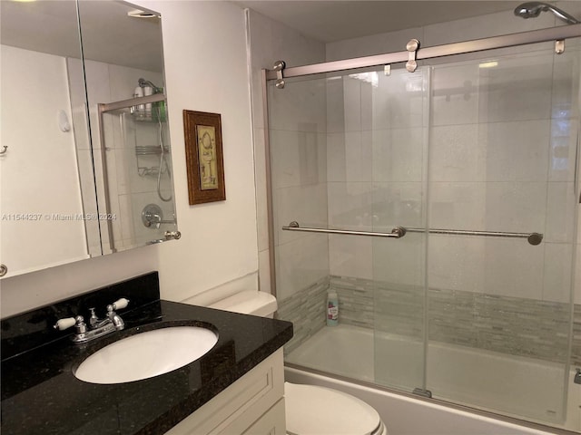 full bathroom featuring combined bath / shower with glass door, toilet, and vanity