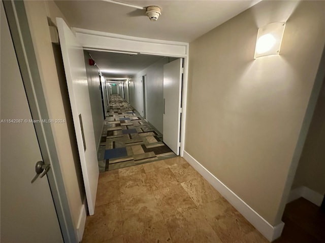 hall with dark tile flooring