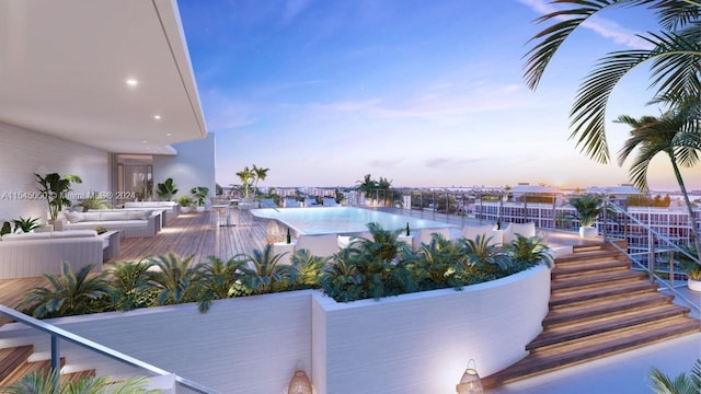 pool at dusk featuring an outdoor living space and a deck