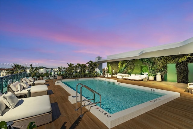 9901 W Bay Harbor Dr Unit 303, Bay Harbor Islands, FL 33154 - pool at dusk featuring a wooden deck, a community pool, and an outdoor living space