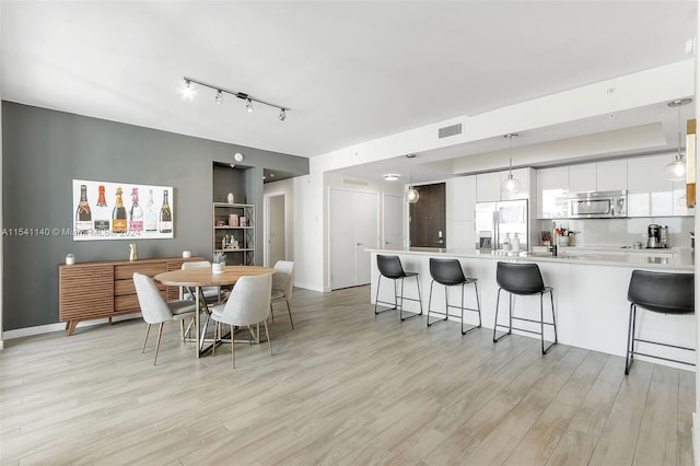 dining room with track lighting and light wood-type flooring