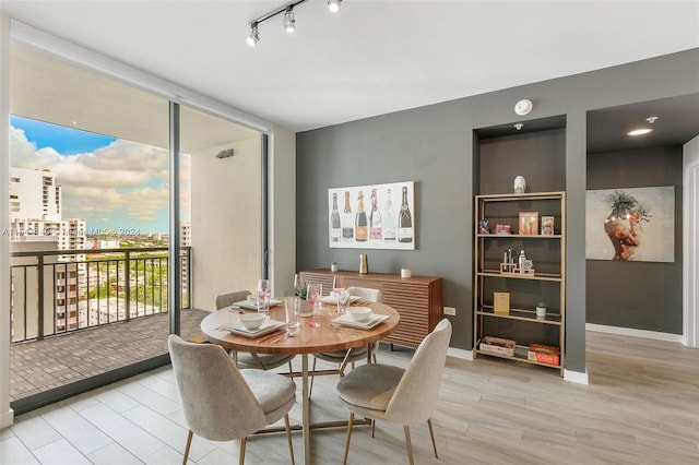 dining area with light wood-type flooring and rail lighting