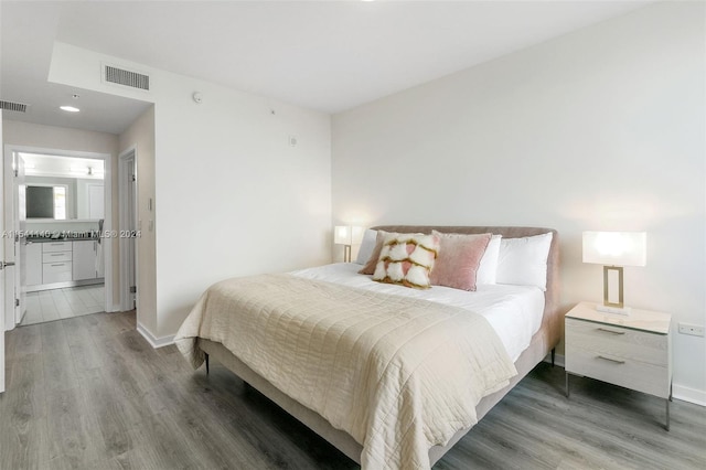 bedroom featuring ensuite bath and hardwood / wood-style flooring