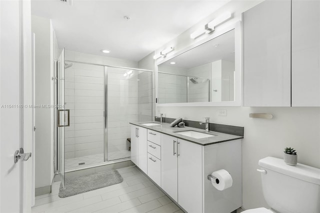 bathroom with toilet, double vanity, tile flooring, and a shower with door