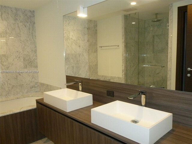 bathroom featuring dual vanity, tiled shower, and tile walls