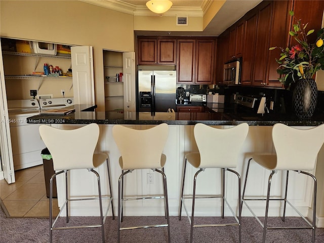 kitchen with stainless steel appliances, light tile flooring, tasteful backsplash, ornamental molding, and a breakfast bar area