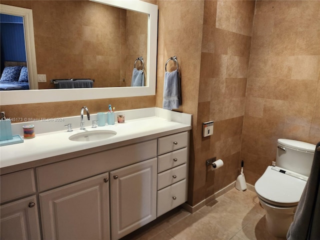 bathroom with toilet, vanity with extensive cabinet space, tile flooring, and tile walls