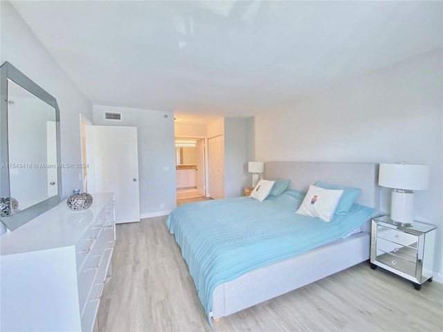 bedroom featuring connected bathroom and light wood-type flooring