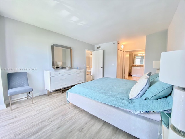 bedroom with ensuite bathroom and light hardwood / wood-style flooring