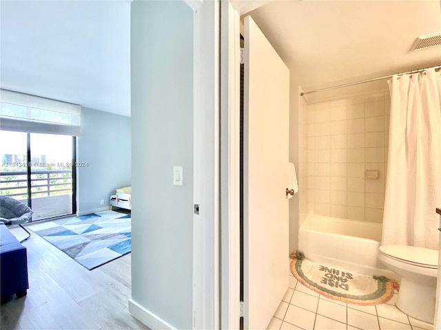 bathroom with shower / tub combo, tile floors, and toilet