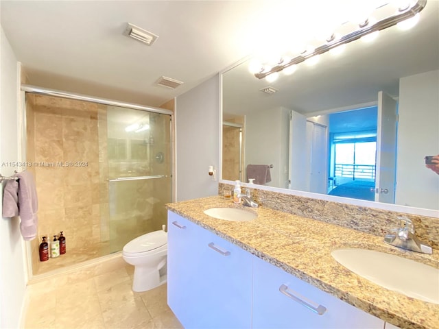 bathroom featuring toilet, dual bowl vanity, tile flooring, and a shower with door