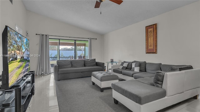 tiled living room featuring lofted ceiling, ceiling fan, a water view, and a textured ceiling