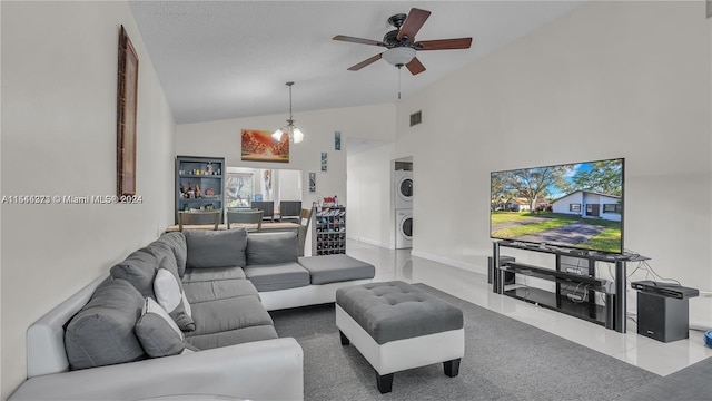 living room with ceiling fan, high vaulted ceiling, stacked washing maching and dryer, and a textured ceiling