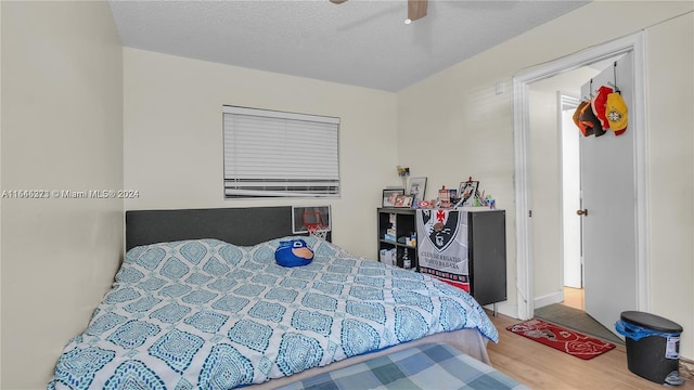 bedroom with hardwood / wood-style flooring, ceiling fan, and a textured ceiling