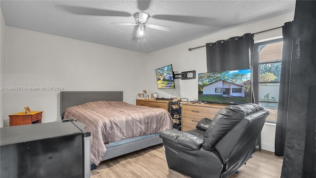 bedroom featuring ceiling fan, a textured ceiling, and light wood-type flooring