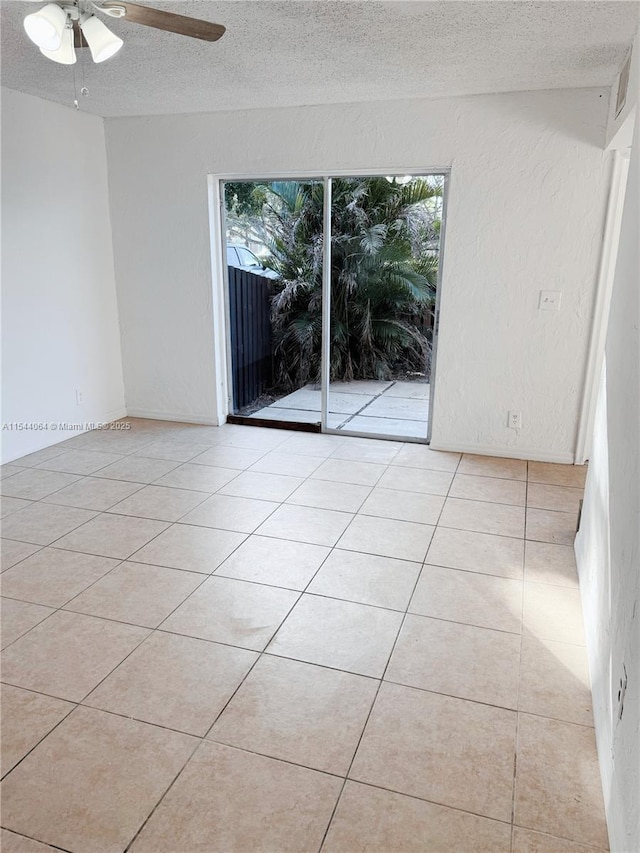 empty room with ceiling fan, a textured ceiling, and light tile patterned flooring