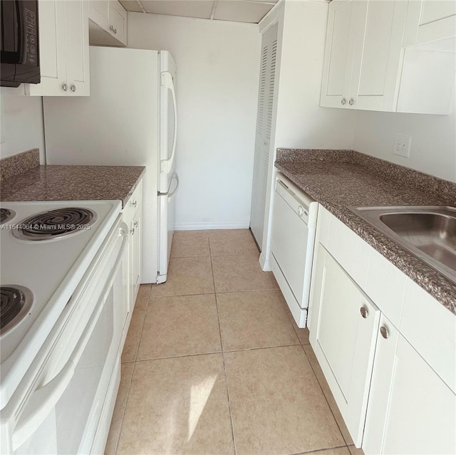 kitchen with white appliances, sink, light tile patterned floors, and white cabinets