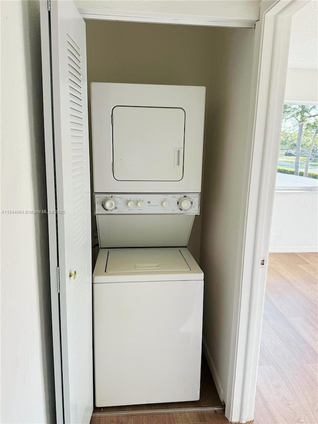 clothes washing area with stacked washer / drying machine and light hardwood / wood-style floors