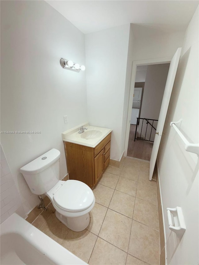 bathroom featuring tile patterned flooring, vanity, a washtub, and toilet