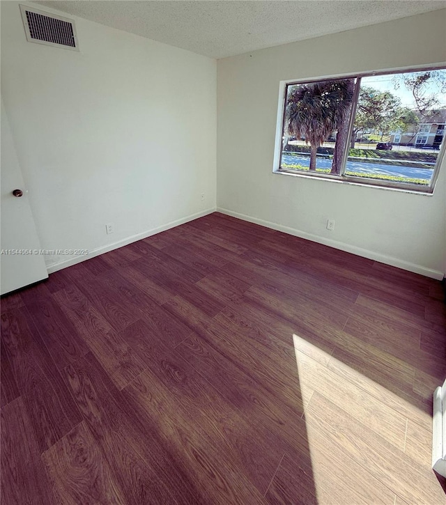 empty room featuring wood-type flooring and a textured ceiling