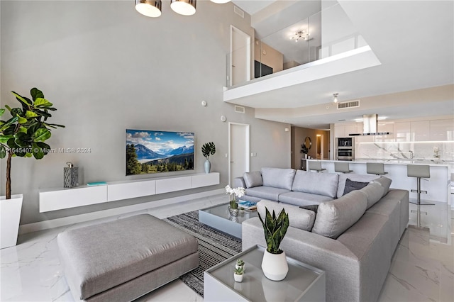 living room with an inviting chandelier, light tile floors, and a towering ceiling