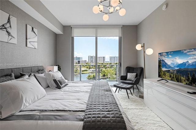 bedroom featuring floor to ceiling windows, a chandelier, and a water view