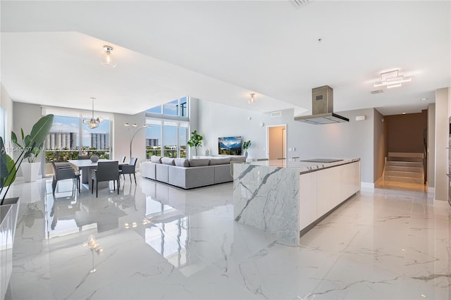 kitchen with white cabinets, light tile flooring, light stone countertops, island range hood, and decorative light fixtures