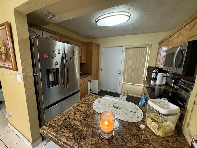 kitchen featuring appliances with stainless steel finishes, light tile patterned floors, and a textured ceiling