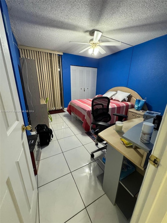 bedroom featuring light tile patterned floors, a closet, a textured ceiling, and ceiling fan