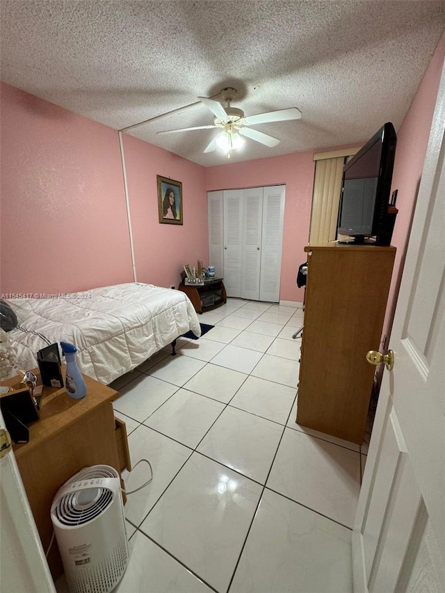 bedroom featuring light tile patterned flooring, ceiling fan, a textured ceiling, and a closet