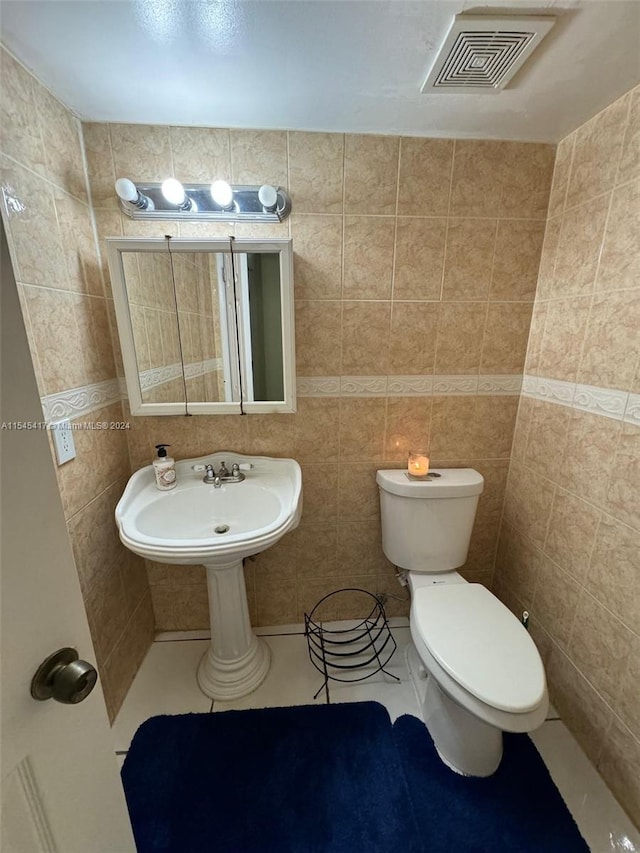 bathroom with tile patterned flooring, sink, tile walls, and toilet