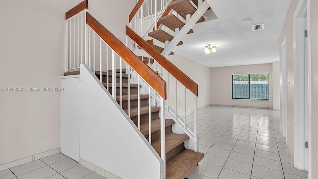 stairway with a textured ceiling and tile patterned floors