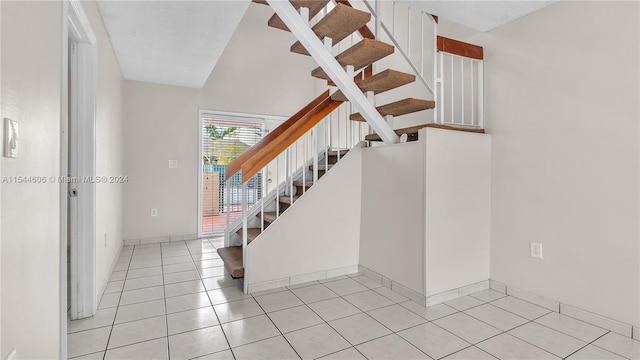 staircase featuring a textured ceiling and tile patterned floors