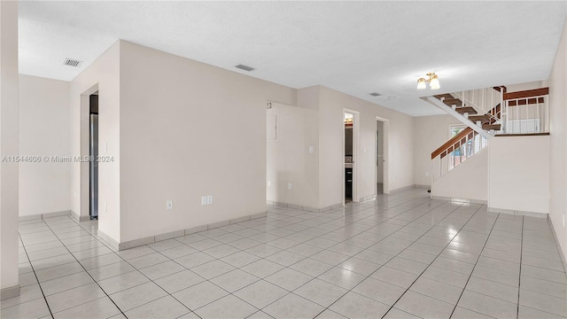 unfurnished room with light tile patterned floors and a textured ceiling