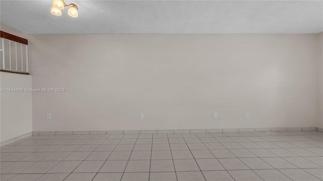 empty room featuring a textured ceiling and light tile patterned floors