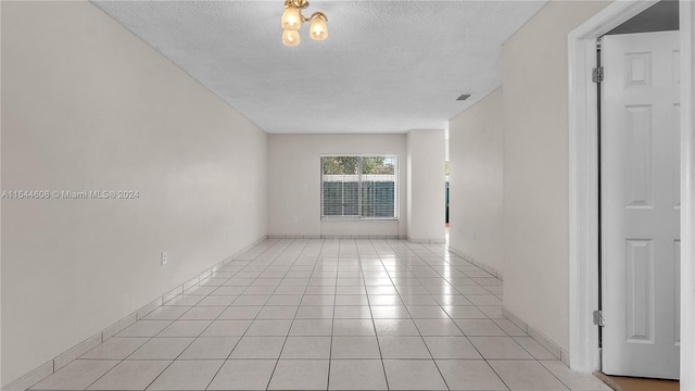 spare room featuring light tile patterned flooring and a textured ceiling