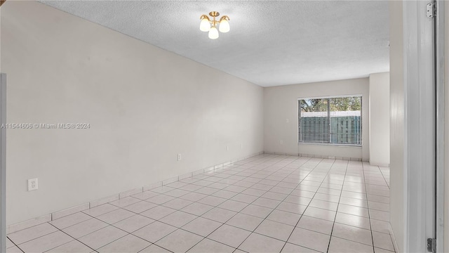 spare room with a textured ceiling and light tile patterned floors