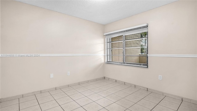 unfurnished room with a textured ceiling and light tile patterned floors