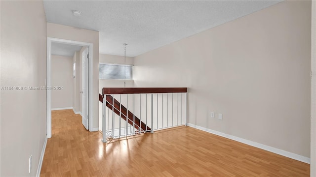 hallway featuring light wood-type flooring and a textured ceiling