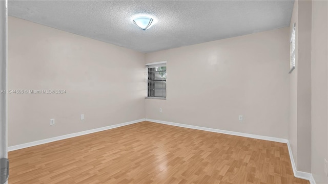 spare room with a textured ceiling and hardwood / wood-style floors