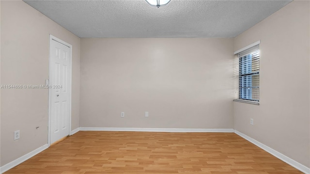 empty room featuring a textured ceiling and light hardwood / wood-style flooring