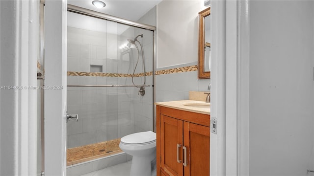 bathroom with vanity, toilet, tile walls, and a shower with shower door