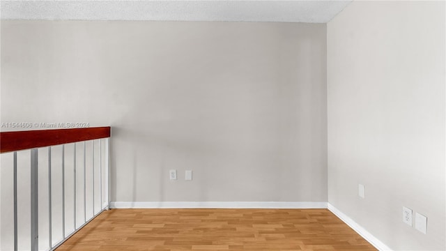 unfurnished room with a textured ceiling and light hardwood / wood-style floors