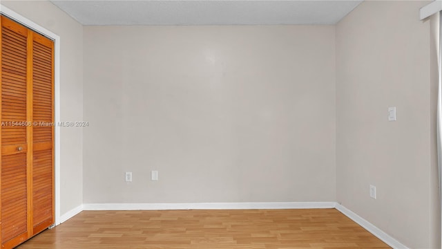 unfurnished bedroom featuring a textured ceiling, a closet, and hardwood / wood-style flooring